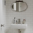 Ванные комнаты выполнены в светлых тонах с использованием белого кафеля. Современный кран отлично сочетается с винтажным зеркалом.