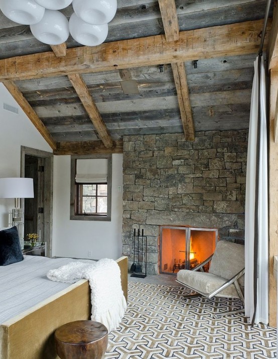 Эклектичная, но очень уютная спальня с намеком на французскую деревню. Дизайн камина отлично сочетается с креслом и прикроватным светильником.