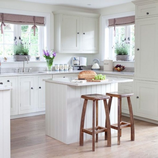 Две высокие деревянные табуретки у кухонного острова в белой кухне средиземноморского стиля.