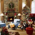 Елка украшенная золотыми и красными украшениями. Над камином рождественский венок, а у камина украшенные подсвечники.