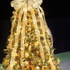 Небольшая новогодняя елка с золотистыми елочными игрушками и лентами.