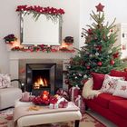 Стильная традиционная новогодняя елка с красными и белыми украшениями. Камин украшен гирляндой.