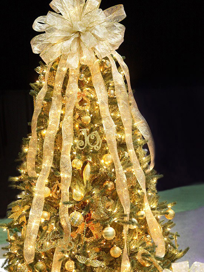 Небольшая новогодняя елка с золотистыми елочными игрушками и лентами.