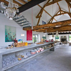 Длинная бетонная кухонная столешница проходящая по центру помещения определяет кухню.