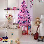 Необычно розовая искусственная ёлочка прекрасно украшает светлую детскую. Комната также украшена гирляндами и рождественским венком на кровати.