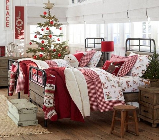 Детская спальня с традиционной елкой, постельным бельем в рождественских цветах и большие носки для подарков на каждой кровати.