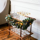 Сервировочный столик украшенный новогодней гирляндой с лимонами.