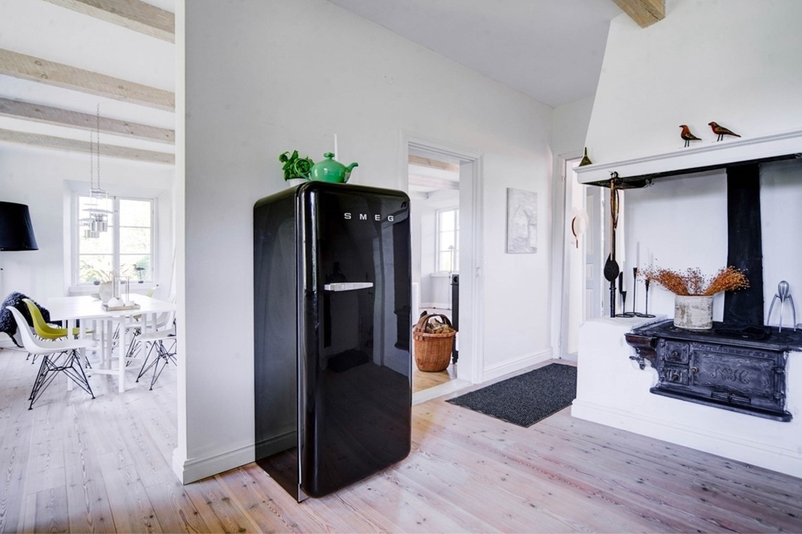 Старый очаг хоть и не используется по назначению, однако является важным элементом декора. Черный холодильник SMEG гармонично вписался в интерьер кухни рядом со старым очагом.