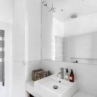 Белый цвет и огромное зеркало визуально расширяют помещение маленькой ванной комнаты.