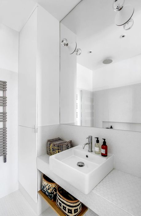 Белый цвет и огромное зеркало визуально расширяют помещение маленькой ванной комнаты.