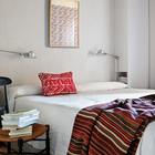 Интерьер спальни минималистичен, настроение задается красочными этническими орнаментами аксессуаров.