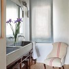 Интерьер ванной выдержан в общем стиле квартиры, с деревянным полом и вниманием к деталям. Размер ванной позволил поставить там кресло.