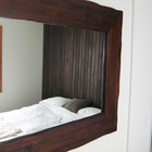 Отражение гостевой спальни в зеркале рядом с кроватью.