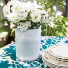 Белая ваза с цветами освежает дизайн столовой на террасе и радует глаз.