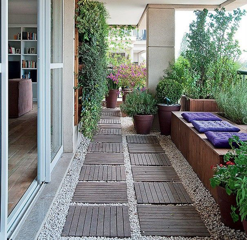 Терраса в многоэтажном доме. Зелень, гравий, деревянные дорожки и скамья с подушками создают нужную атмосферу.