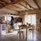 Кухня-столовая с бетонными полами, открытой каменной кладкой и открытыми толстыми деревянными балками.