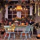Отлично украшенный тыквами, свечками, листьями стол на террасе у дома.