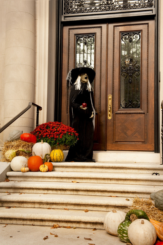 Еще один вариант ведьмы с тыквами и цветами у входа в дом.