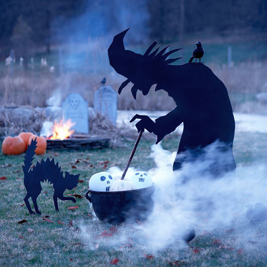 Фигура ведьмы варящей зелье во дворе дома. Фигуру можно вырезать из фанеры и покрасить черной краской.