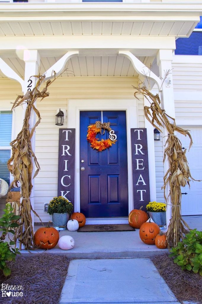 Тыквы, фонари Джека, кукурузные стебли, вазоны с цветами и венок из осенней листвы украшают вход в этот дом.