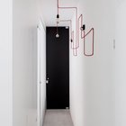 Узкий коридор ведущий к спальням украшен витиевато уложенным в геометрические фигуры красным проводом для ламп.