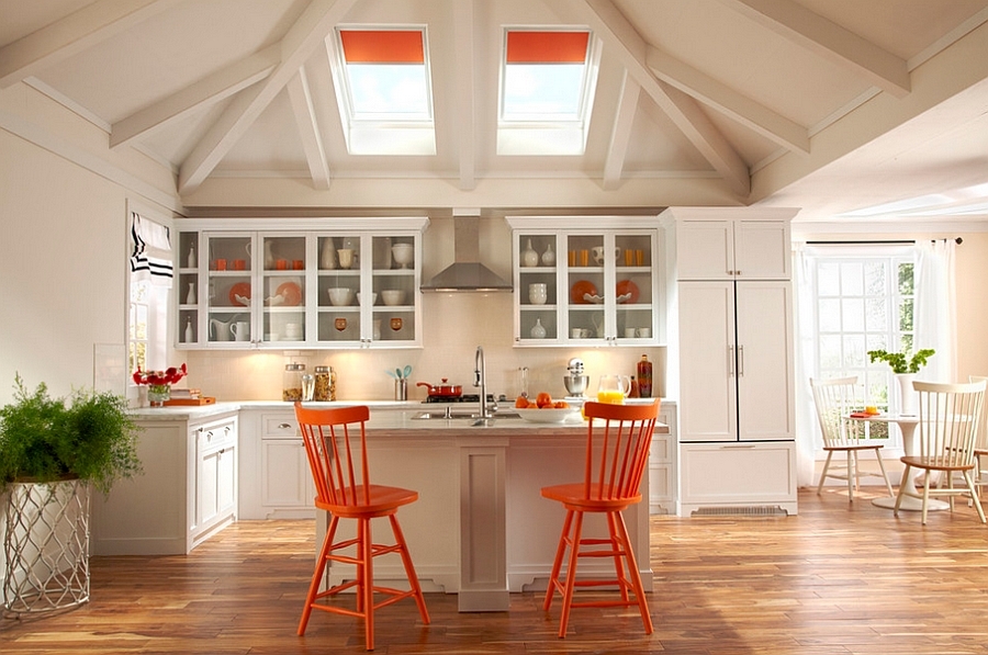 Совпадение цвета рулонных штор на мансардных окнах, барных стульев и некоторой посуды объединяет интерьер этой кухни