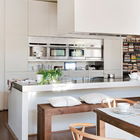 Рабочей поверхностью в кухне служит бетонный кухонный остров со столешницей покрытой нержавейкой. Он же служит и барной стойкой. Вместо барных стульев дизайнер использовал скамью.