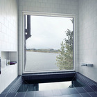 Удивительная ванная комната с ванной в полу и огромным окном с видом на море.