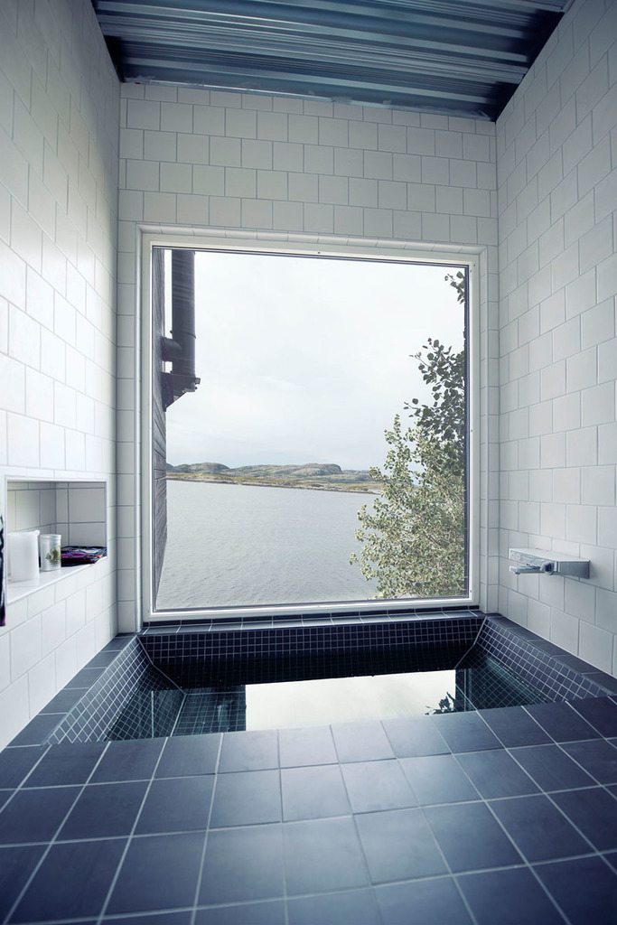 Удивительная ванная комната с ванной в полу и огромным окном с видом на море.
