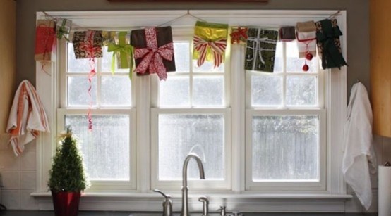Гирлянда из подарочных коробок и елочка на подоконнике украшают кухонное окно