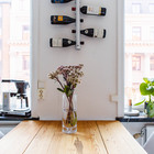 Креативный держатель для винных бутылок над обеденным столом и кофеварка на подоконнике экономят место на столе.