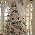 Большая новогодняя елка украшенная белыми и розовыми украшениями, искусственным мехом и гирляндой.