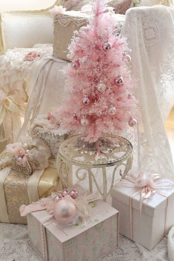 Розовая елочка украшенная золотистыми шариками. Елка окружена подарками в соответствующим образом декорированных коробках.
