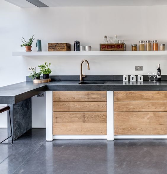 Темная бетонная кухонная столешница контрастирует со светлой древесиной кухонного фасада.