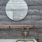 Медные трубы в стиле лофт хорошо смотрятся на фоне бетона в ванной.