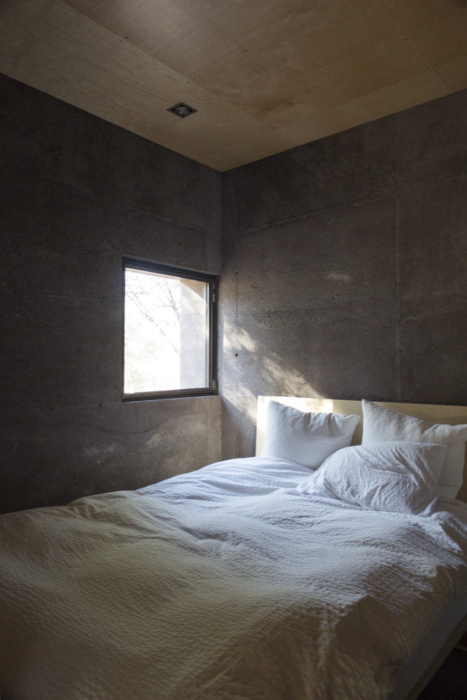 Минималистский интерьер спальни. Потолок отделан деревом