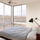 Одна из спален дома с угловым окном и потрясающим видом на пустыню.