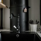 Винтажного вида черный кран на кухне не выделяется на фоне черной вентиляционной трубы, а выглядит стильно и органично.