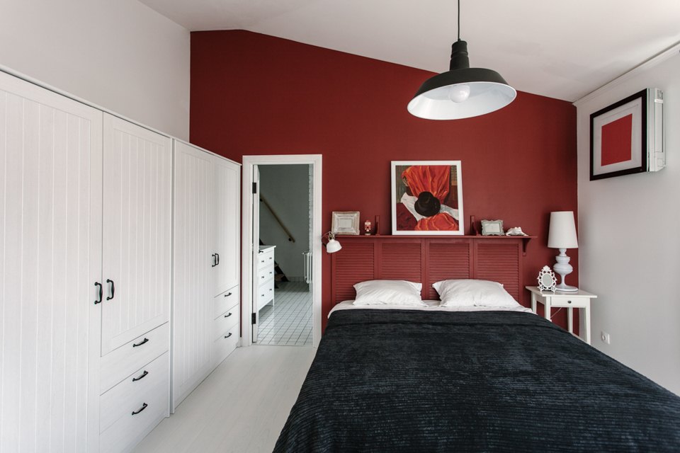 В спальне бордовая акцентная стена подчеркивает наклонный потолок добавляя спальне романтики