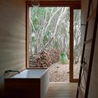 Деревянная отделка ванной комнаты подчеркивает связь с природой за большим размером во всю стену окном.