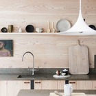 Теплые оттенки и текстуры дерева в отделке кухни оттеняются серым бетоном кухонных столешниц.