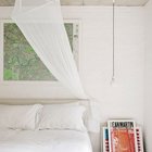 Спальня с окрашенными в белый цвет кирпичными стенами, картой города в изголовье и свисающими с потолка плафонами в качестве прикроватных светильников.