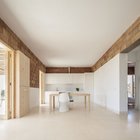 Белая минималистская кухня расположена в торце жилой комнаты и не доминирует в интерьере.