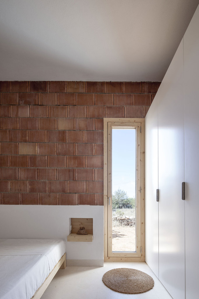 Изголовьем кровати служит нижняя оштукатуренная часть стены, а вместо прикроватных полочек деревянные полочки.