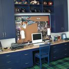 Абсолютно взрослый домашний офис в детской с синими шкафами и полкой-столешницей во всю стену.