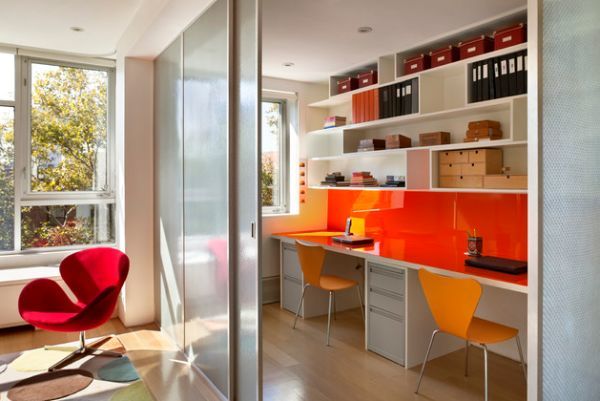 Современный яркий домашний офис с красной столешницей и оранжевыми стульями.