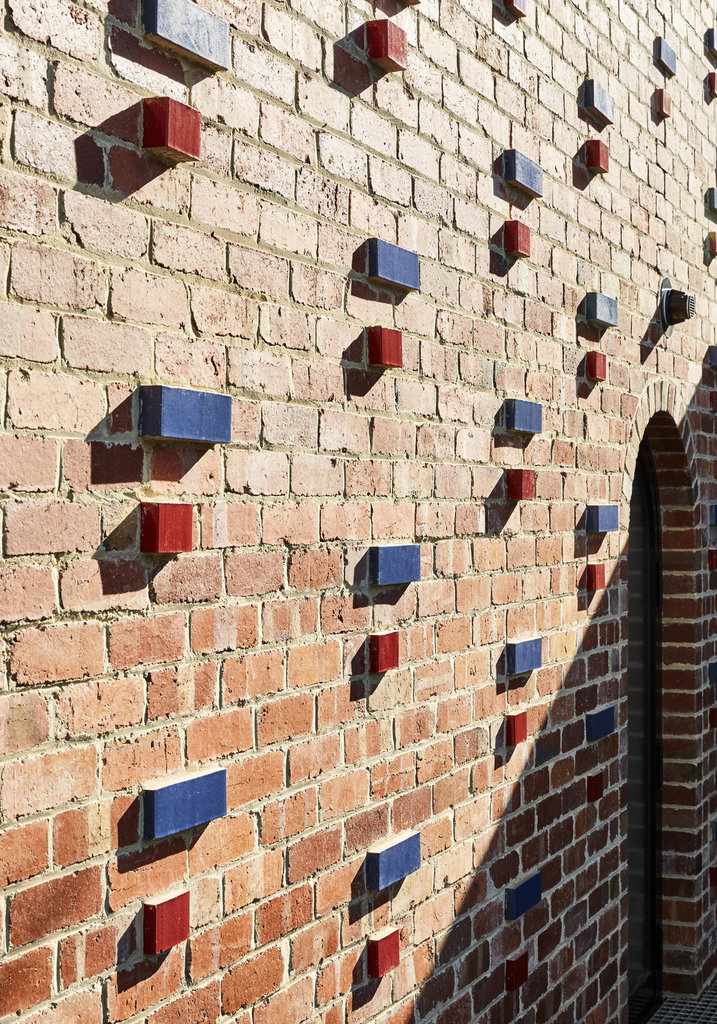 Красные и синие кирпичи добавленные в кирпичную кладку разнообразят и украшают фасад выходящий во двор.