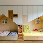 Одну из стен детской полностью занимают белые шкафы с нишами в виде домиков или коттеджей.