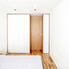 Интерьер минималистской спальни построен на контрасте холодного белого и теплой древесной текстуры.