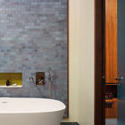В ванной комнате рядом с главной спальней уникальным образом использована кафельная плитка. Кафельная плитка на стене рядом с отдельно стоящей ванной выложена ковром и обрамлена в деревянную рамку.